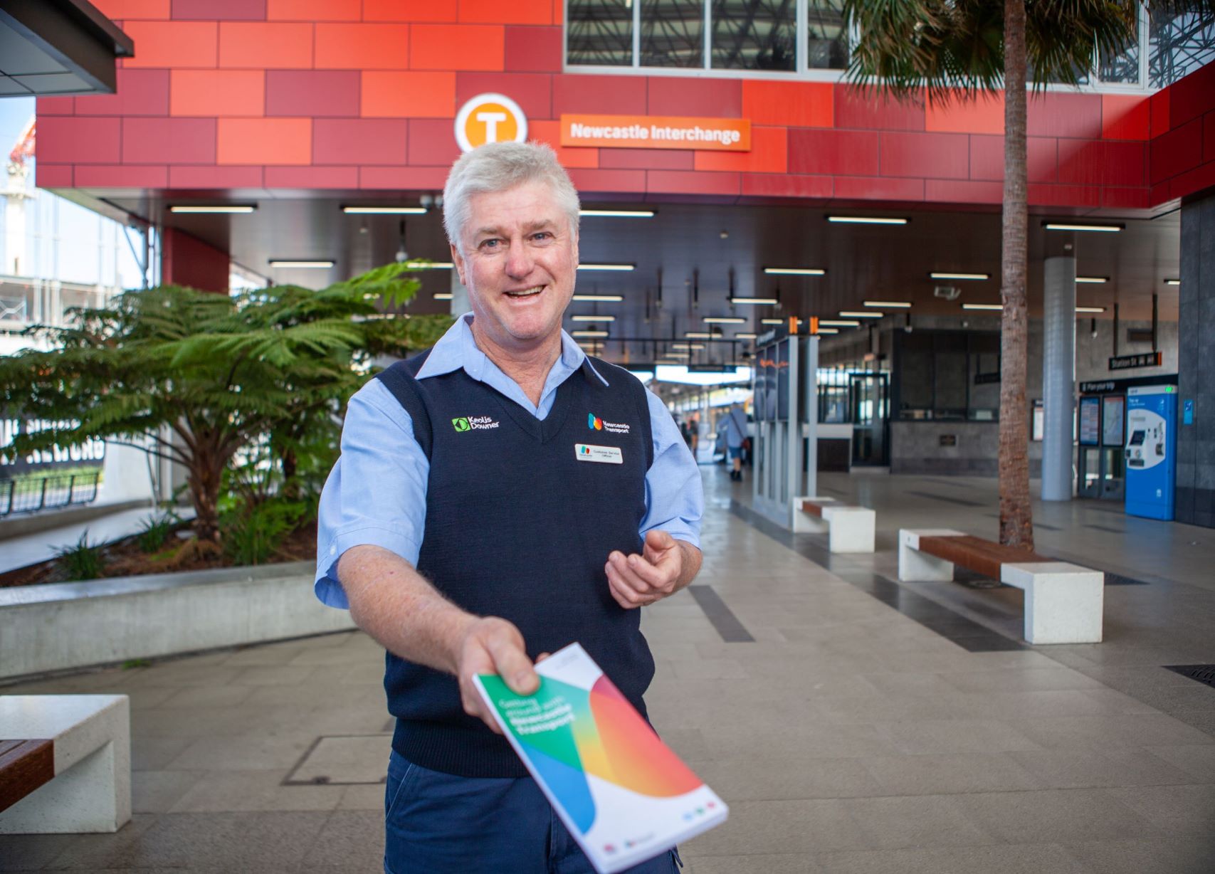 Newcastle Transport customer service officer smiling and holding out a brochure