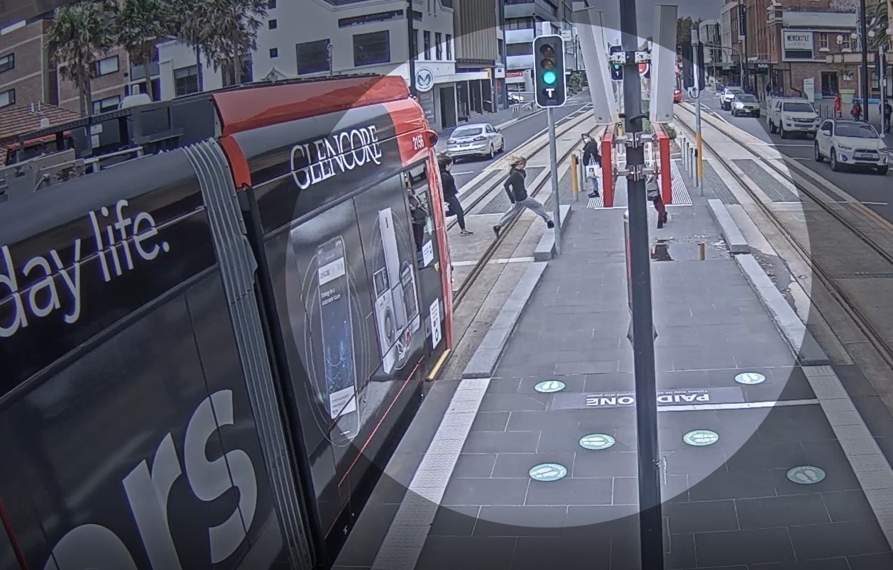CCTV screenshot showing pedestrians running in front of a tram
